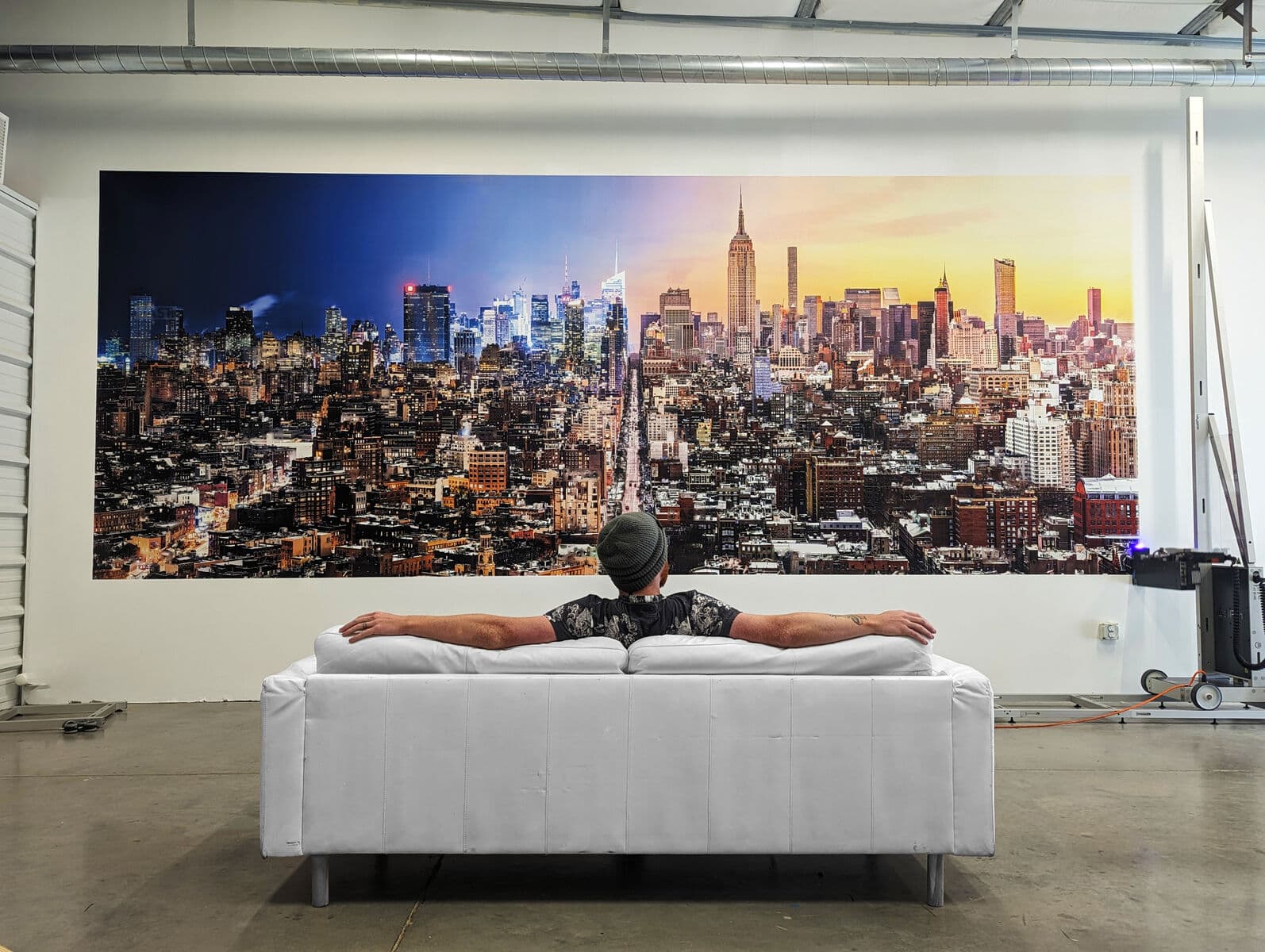 Floor-to-ceiling mural of the New York City skyline printed directly on a showroom wall, with a couch staged in front of it